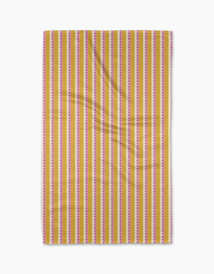 Stripe Mania by Geometry is a rectangular yellow tea towel with vertical red, pink, and white stripes, made from Geoweave™ fabric and shown flat with subtle folds on a white background.