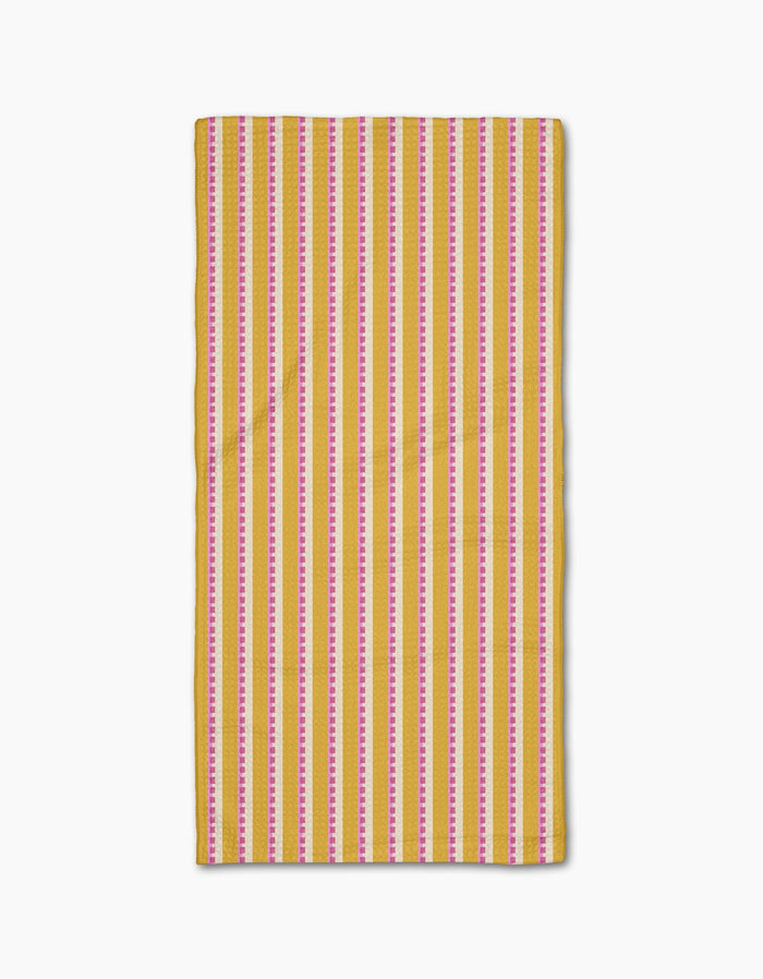 The Geometry Stripe Mania napkin, made from Geoweave fabric, features vertical yellow, pink, and white stripes and is displayed flat on a white background.