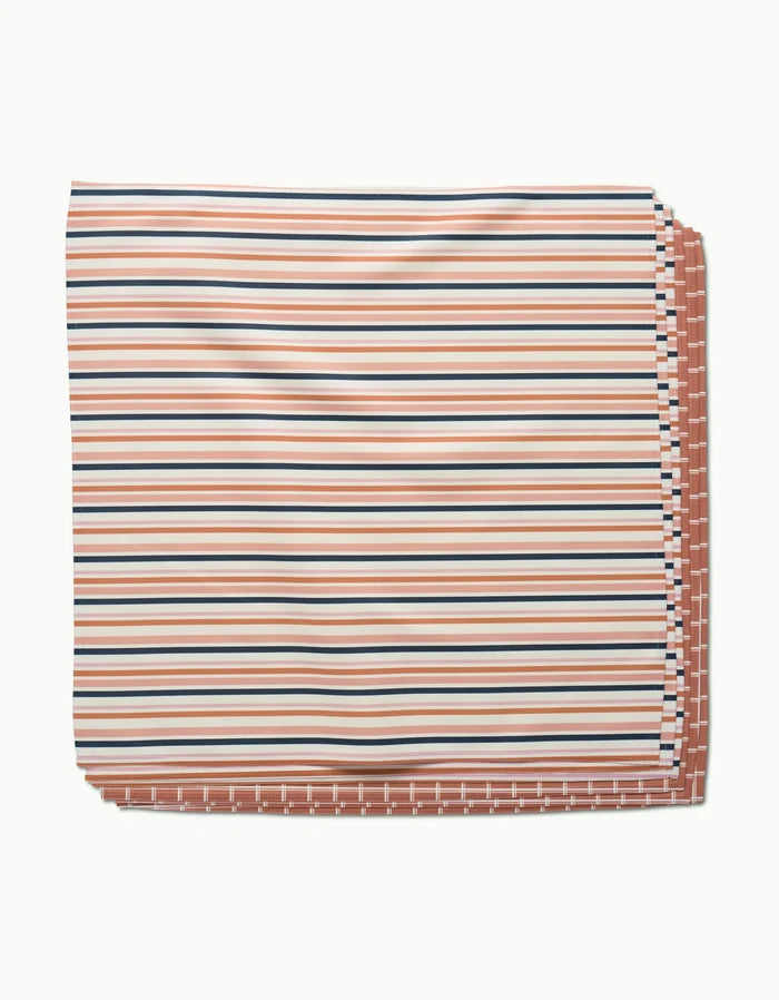 The Striped Harvest blanket by Charlie Rowan Designs features Geosuede fabric with rust, navy blue, and white horizontal stripes, plus a reversible side with a rust and white checkered pattern.