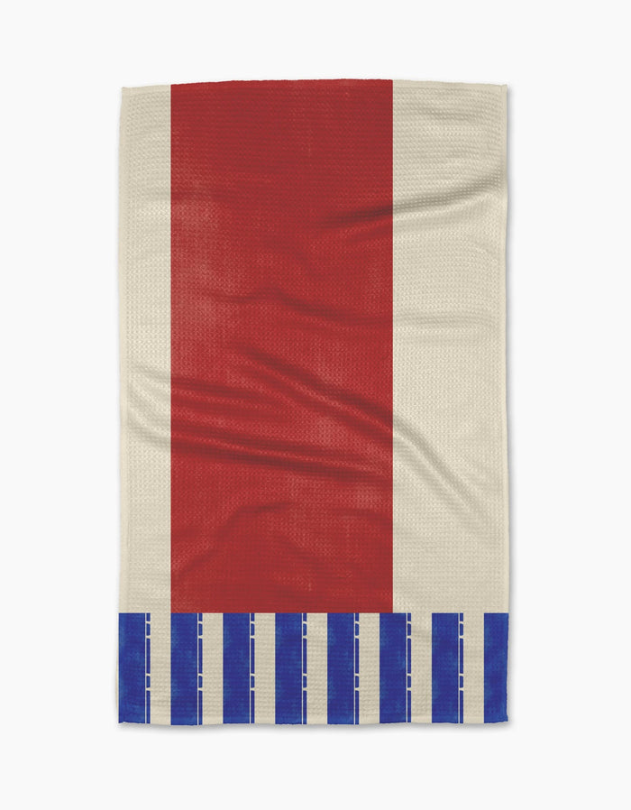 The Striped Heart Red tea towel by Geometry is rectangular, made of Geoweave fabric, with a large vertical red stripe in the center, a cream background, and blue rectangles along the bottom edge.