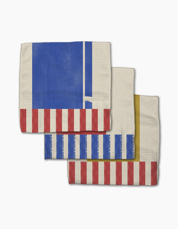 Three folded Geometry Striped Heart dishcloths with bold blue, red, yellow, and white geometric stripes and rectangles overlap on a white background. Made from durable Geoweave fabric for superior absorbency and quick drying.