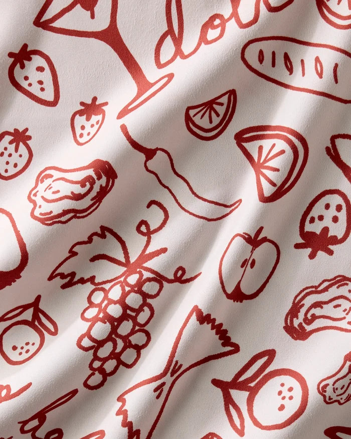 The Summer Air reusable cloth napkins by Geometry feature red line drawings of foods on cream-colored, slightly wrinkled fabric, offering a charming and eco-friendly touch to your table setting.