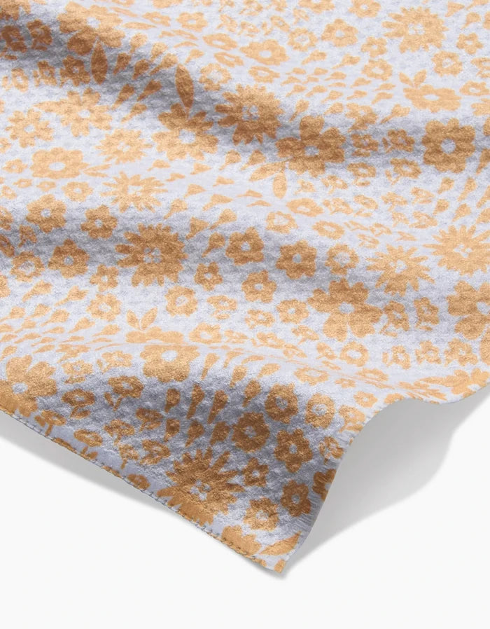 A close-up of the Hufton Studio Summer Fields bar towel, made from ultra-absorbent fabric with a light blue background and an all-over pattern of small brown flowers and leaves. The towel appears slightly wrinkled on a white surface.