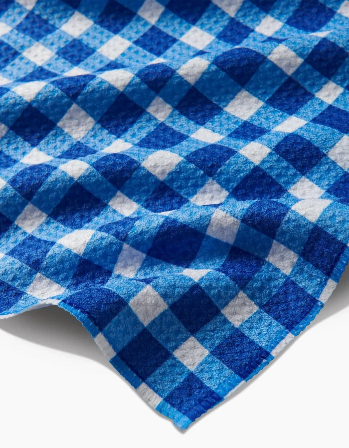 A close-up of the Danelys Sidron Summer Plaid Bar Towel, featuring blue and white checkered Geoweave fabric with a textured surface and visible folds, displayed on a white background.