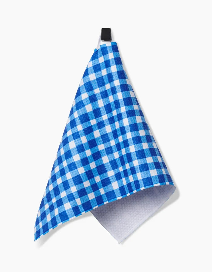 A blue and white Summer Plaid bar towel by Danelys Sidron, crafted from ultra-absorbent Geoweave fabric, hangs from a black loop against a plain white background.