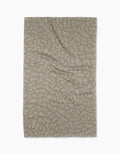 A rectangular, beige Sun Kissed tea towel by Geometry, crafted from eco-friendly Geoweave fabric with an abstract leaf pattern, is laid flat on a white background.