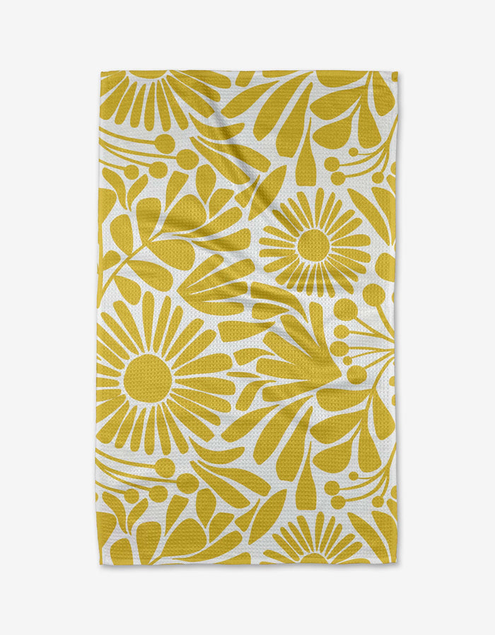 The Sunlit Blooms tea towel by Lisa Nelson features bold yellow and white daisy-like flowers with abstract leaves on white Geoweave fabric. Slightly wrinkled, the rectangular cloth is shown laid flat.