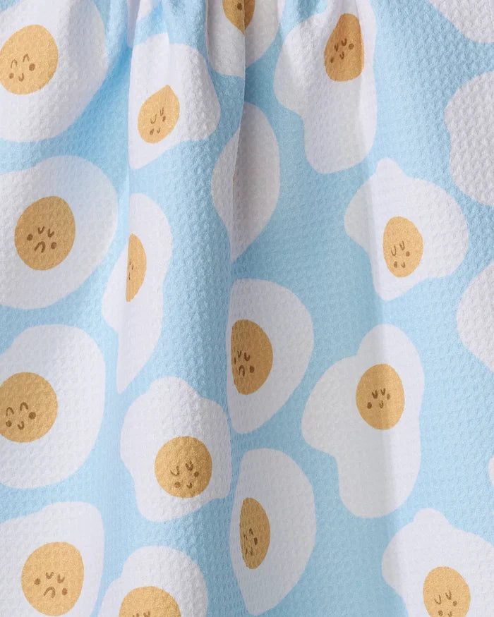 The Sunny Side Up tea towel by Janna Sue Design is made from recycled materials and features a playful sunny-side-up egg pattern with cute faces. Its textured, waffle-like surface adds charm and makes it ultra-absorbent for your kitchen.
