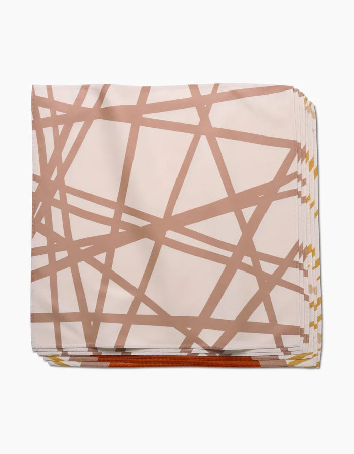The Sunny Stripes Dinner Napkin Set by GEOMETRY is crafted from recycled Geosuede fabric and showcases a modern, geometric design with intersecting brown stripes on a light background.