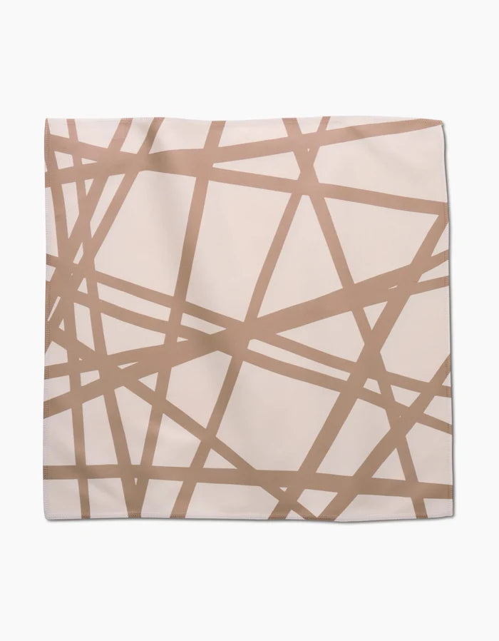 The Sunny Stripes by GEOMETRY is a square Geosuede fabric in beige, showcasing an abstract pattern of intersecting thin brown lines that create irregular geometric shapes.