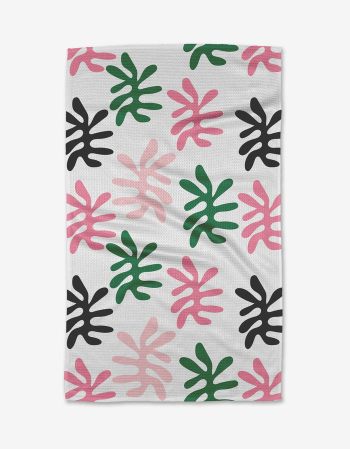 Sunrise by Marina Solodka is a white tea towel with an abstract leaf pattern in pink, black, and green on soft Geoweave fabric.