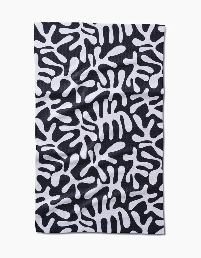 The Sunset tea towel by Marina Solodka features a rectangular, ultra-absorbent Geoweave™ fabric with a black background and abstract white, amoeba-like patterns.