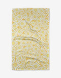 The Rebecca Bobko Sunshine Meadow rectangular cloth, made from ultra-absorbent Geoweave fabric, features yellow and white daisies with large yellow centers on a white background and is shown slightly wrinkled on a white surface.