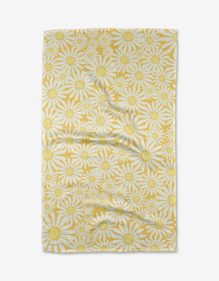 The Rebecca Bobko Sunshine Meadow rectangular cloth, made from ultra-absorbent Geoweave fabric, features yellow and white daisies with large yellow centers on a white background and is shown slightly wrinkled on a white surface.