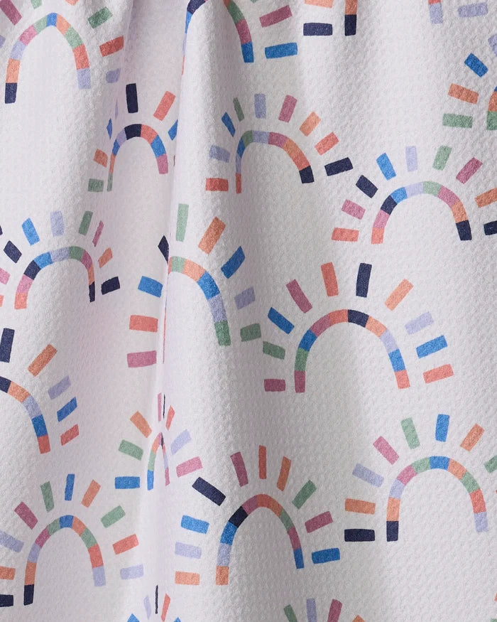 The Sunshine Rainbow kitchen towel by Claire Iglesias features a white textured fabric with colorful semi-circular arches and lines in blue, pink, orange, green, and purple—perfect for brightening up your kitchen.