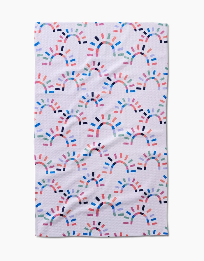 The Sunshine Rainbow towel by Claire Iglesias features a white textured design with colorful, semi-circular rainbow shapes and is crafted from ultra-absorbent Geoweave fabric for superior performance.