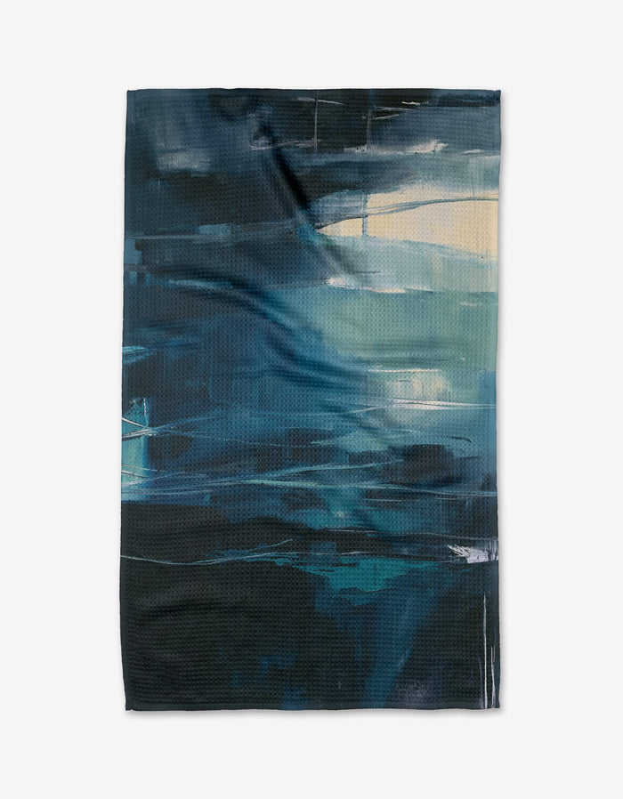 Surface Tension by Jennifer Janesko is a rectangular tea towel made from recycled materials, featuring an abstract design in blue, teal, black, and beige that evokes swirling water or waves.