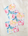 The Suzzy dishcloth set by Ania Zwara Art includes three super-absorbent towels featuring a vibrant floral pattern with pink, peach, and yellow flowers plus green leaves on a light marble background.