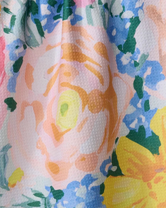 Close-up of Suzzy by Ania Zwara Art: a vibrant kitchen tea towel featuring large pink, yellow, and orange flowers with green leaves and light blue accents. Its textured weave adds a tactile, cheerful touch to your kitchen.