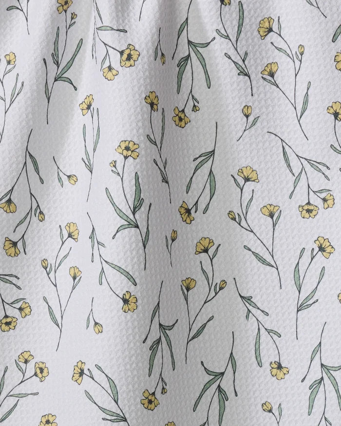 The Sweet Little Nothings dish towel by Ashley Celena features absorbent white textured fabric adorned with small yellow flowers and green stems, adding a charming touch to any kitchen.