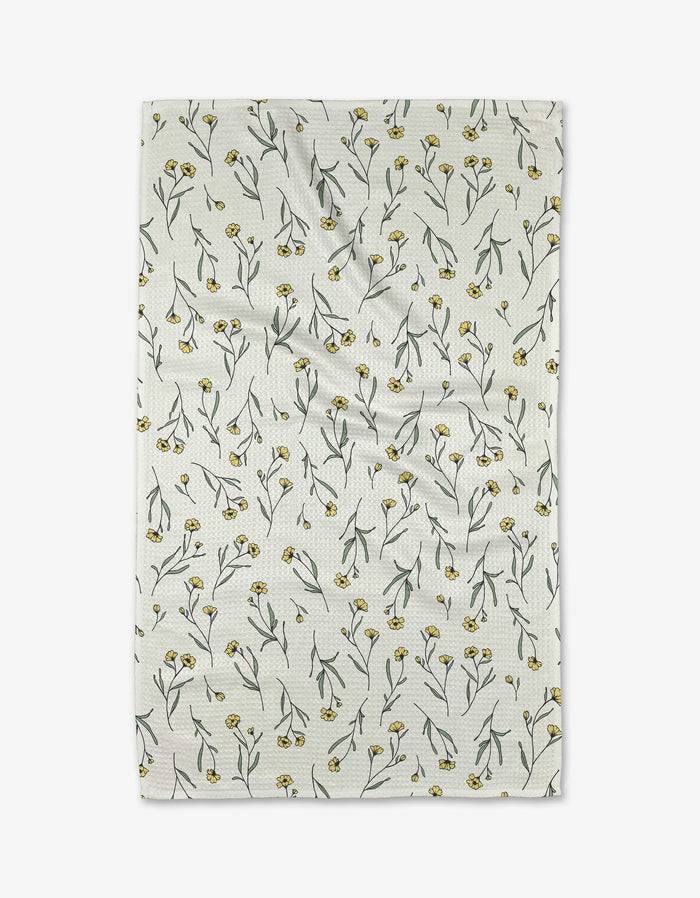 The Sweet Little Nothings tea towel by Ashley Celena features a white textured Geoweave fabric adorned with a repeating pattern of small yellow flowers and green stems scattered across the surface.