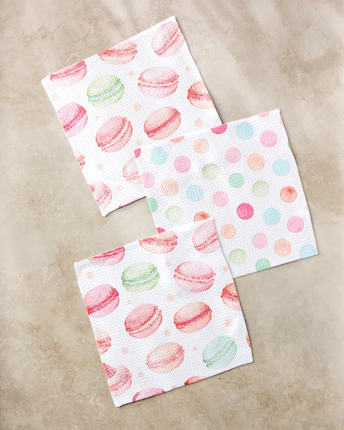 Three Elena Fay "Sweet Macarons" recycled napkins are shown on a beige surface—two with pastel macarons, one with pink, green, blue, and orange polka dots.