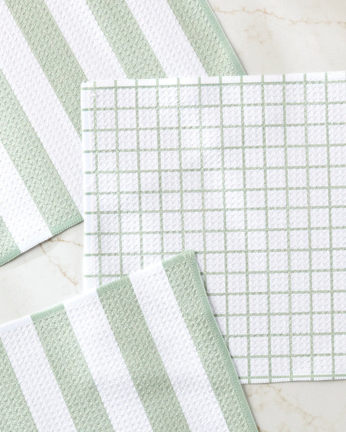 Four Sweet Mint dishcloths by Kailee Wright are arranged on a light countertop—two with bold green and white stripes, two with a grid pattern. The set is neatly positioned, each towel slightly overlapping the next.