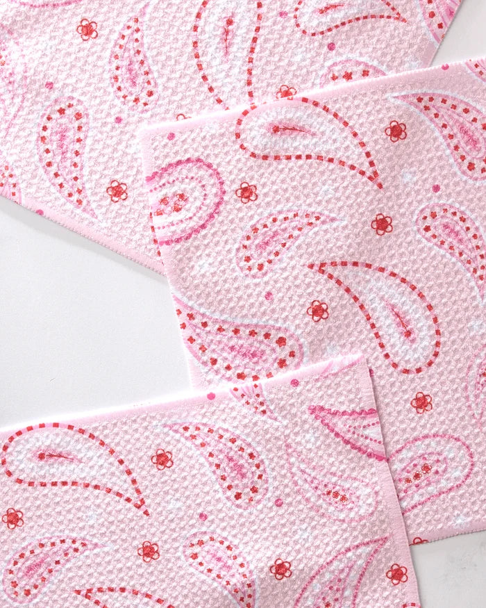 Three overlapping sheets of GEOMETRY Sweet Paisley pink textured paper towels made from recycled materials, featuring red and pink paisleys with small red flowers on a white background.