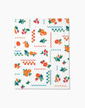 The Aubrey Fairchild Sweet Pickings Butter Blanket offers silky softness with a vibrant design of oranges, strawberries, leaves, and colorful geometric shapes in red, blue, and green.