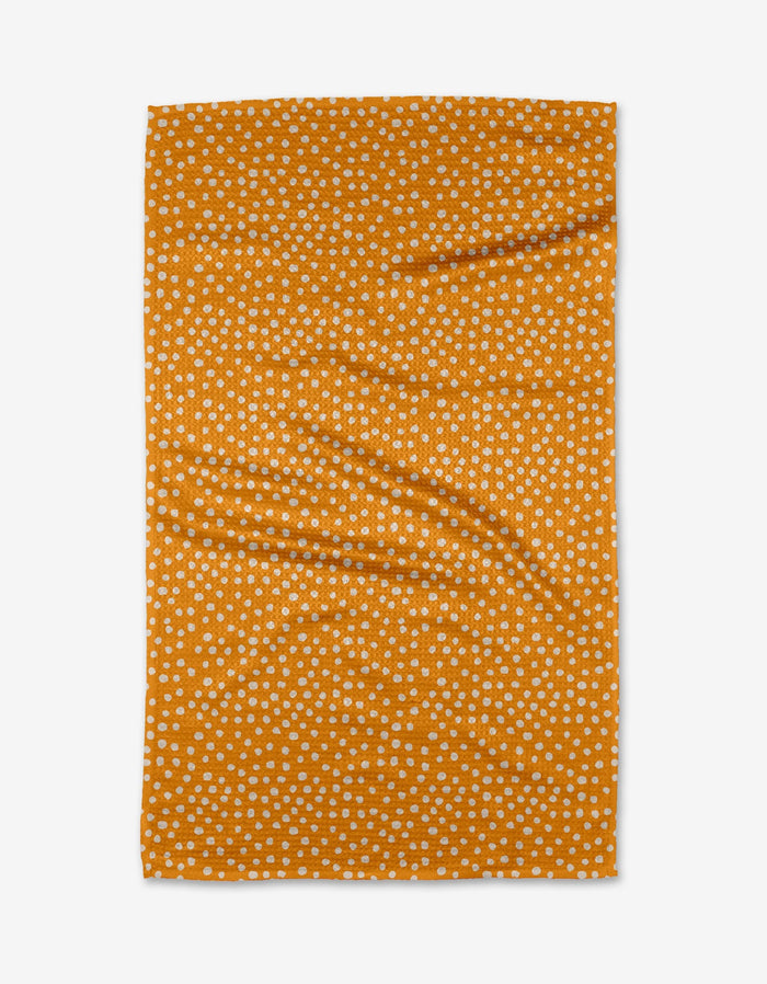 The Purely Kaylie Sweet Sunshine tea towel is orange, rectangular, and made of Geoweave™ fabric with evenly scattered small white polka dots. It’s shown flat with some visible wrinkles.
