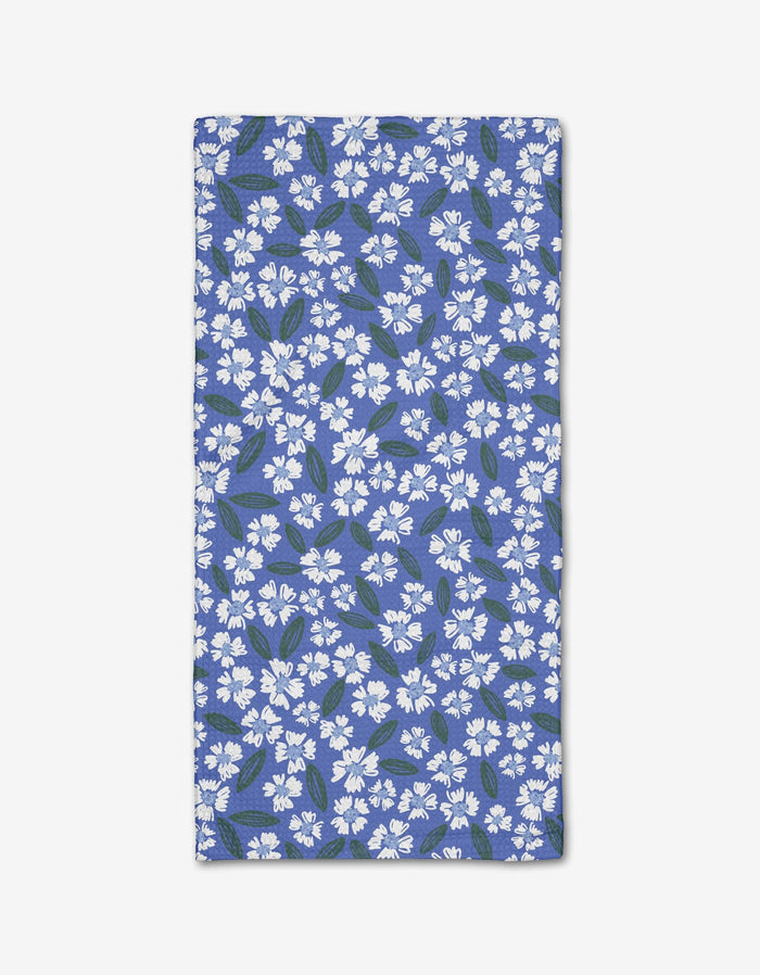 The Hufton Studio Sweetie Floral bar towel, made from eco-friendly Geoweave fabric, features a rectangular blue design with small white flowers and green leaves, shown flat on a white background.