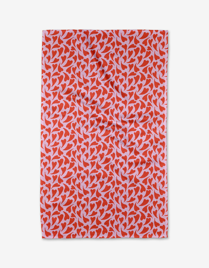 The Swooning Hearts tea towel by Kayla Ann features red abstract heart shapes on pink, is rectangular, quick-drying, made from recycled materials, and shown on a white background.