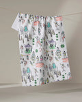 The "Take A Hike" tea towel by Elisabeth Wing features colorful, hand-drawn style illustrations of hikers, mountains, trees, and nature scenes in green, orange, purple, and yellow on white.