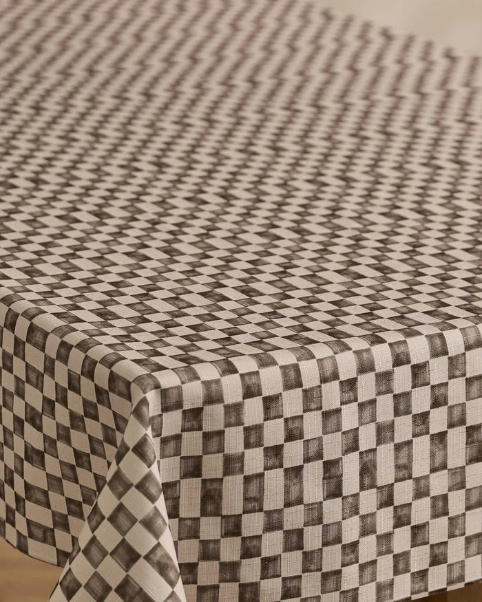 A close-up of Geometrys Tavern rectangular table covered with a stain-resistant, black and white checkered tablecloth featuring a geometric diamond pattern that creates an optical illusion effect.