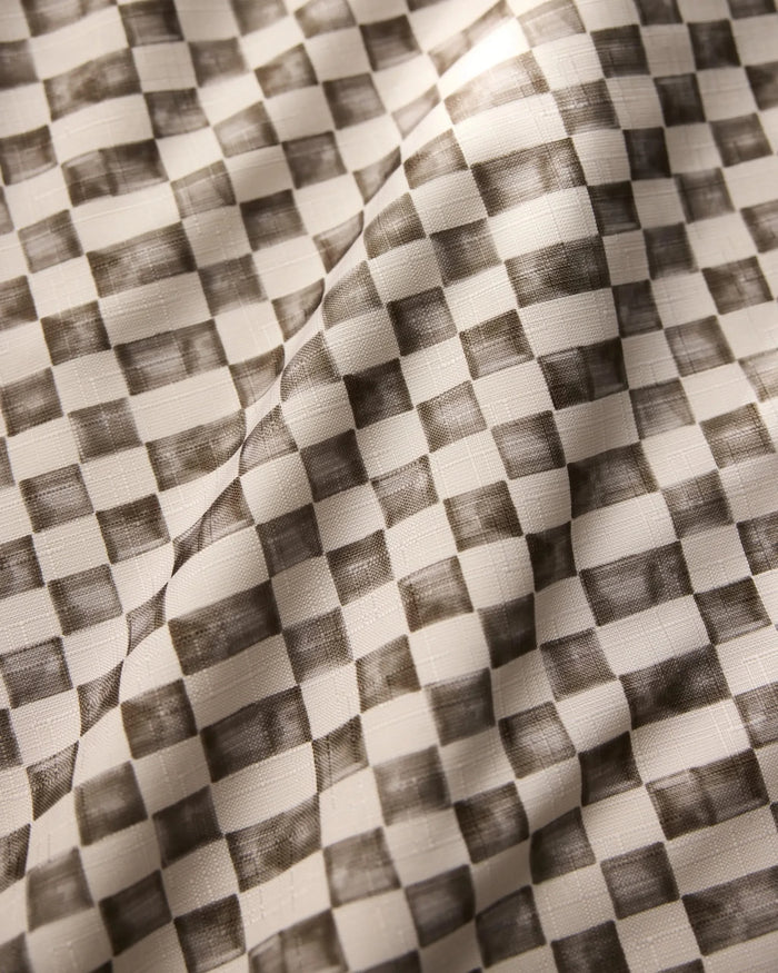 A close-up of Geometry’s Tavern tablecloth reveals a black and white checkered pattern with shaded squares; the stain-resistant fabric has visible folds and a soft, textured surface.