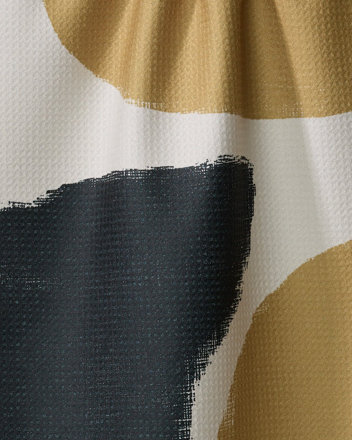 Close-up of the Terzo tea towel by Geometry, featuring abstract mustard yellow, black, and white shapes. This ultra-absorbent towel has soft organic edges and a textured, waffle-like surface for added style and function.