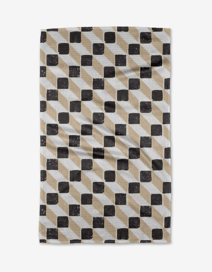 The Tessera tea towel by Studio Jeannot is made from recycled materials and features a textured fabric with a black and beige cube geometric pattern on white, creating a three-dimensional optical illusion effect.