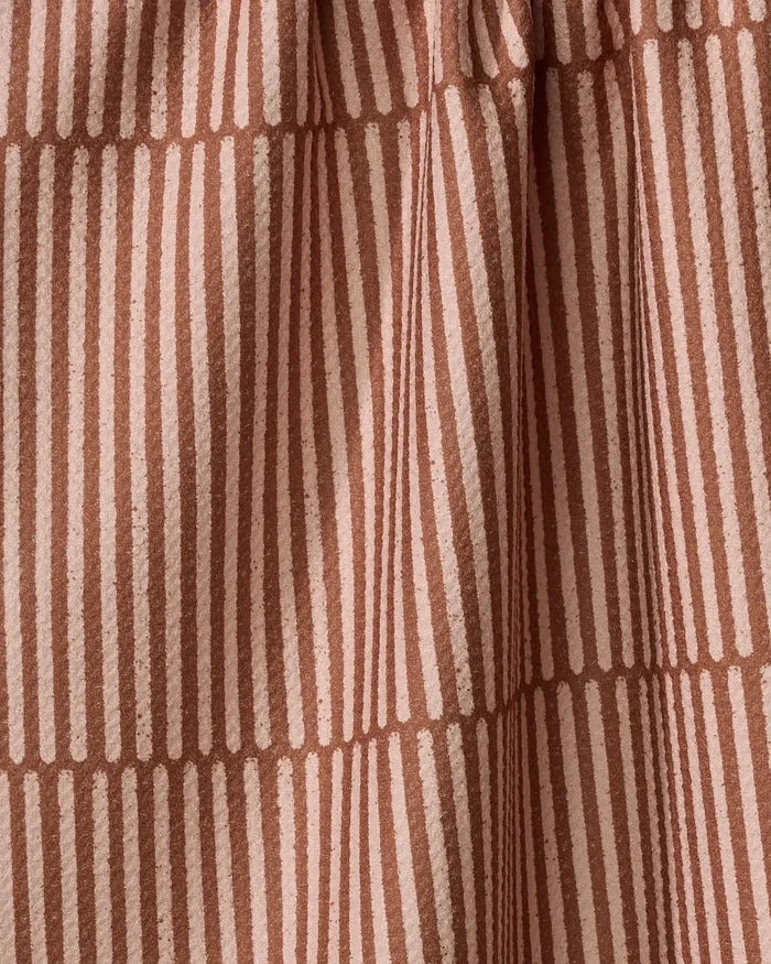 A close-up of Rosa Kichline's Textured Stripe recycled kitchen towel, featuring vertical and horizontal light pinkish-beige stripes on a dusty rose background in a geometric grid pattern with soft folds and texture.