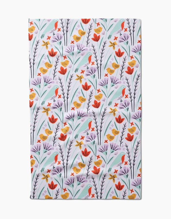 The Thaddeus kitchen towel by Amy MacCready features orange and yellow birds with red, orange, and purple flowers on a white background—crafted from recycled materials.
