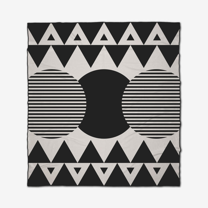 The Outdoors beach blanket by GEOMETRY features a black and white geometric pattern with large circles, a solid black semi-circle center, and a border of black triangles. This quick-drying blanket is perfect for stylish days at the beach.