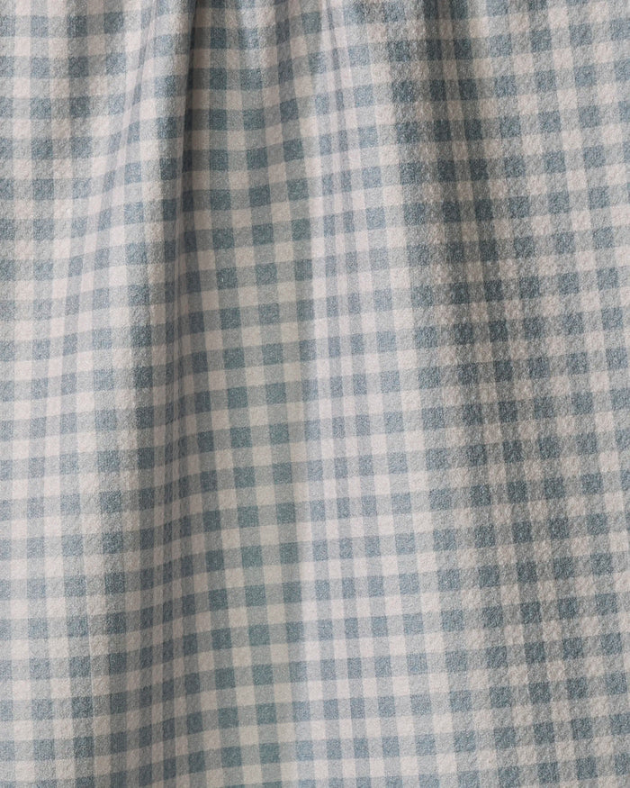 A close-up of the Jenny Keller Tidepool Check kitchen towel showcases its blue and white grid of small squares. Made from recycled materials, the fabric appears slightly gathered or pleated near the top.
