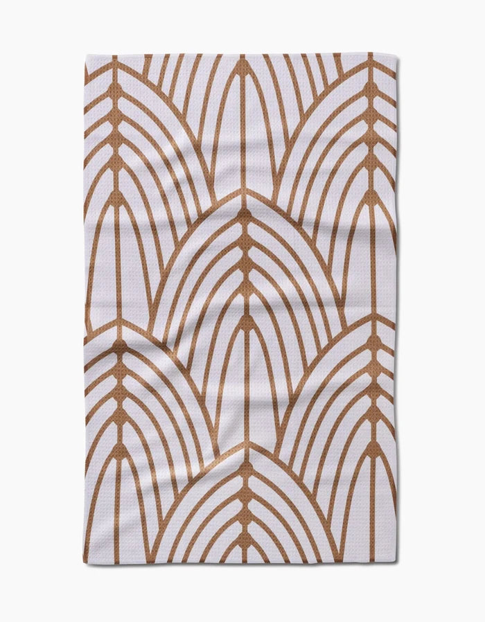 The Tiffany cloth by Amy MacCready is made of white Geoweave fabric and showcases a repeating brown geometric pattern of overlapping arch shapes, similar to stylized leaves or fans, with visible folds and creases.