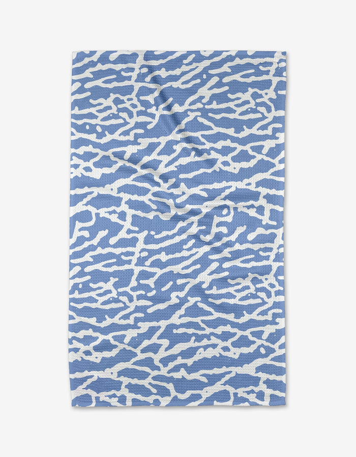 The Sissy Moon Tinker Tea Towel features an abstract pattern of irregular white lines on a light blue background, evoking light on water, and is crafted from eco-friendly materials for sustainable style.
