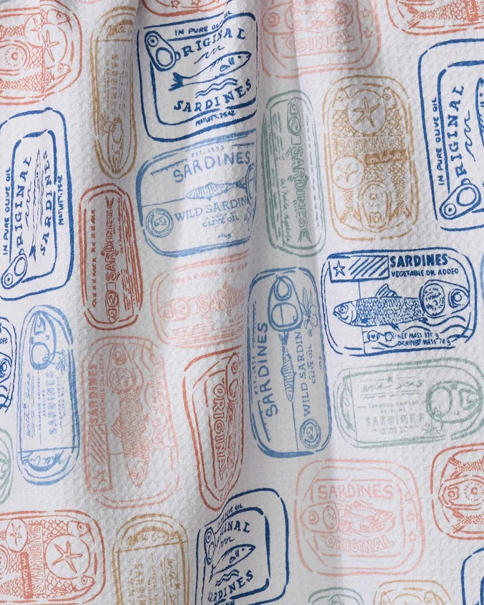The Tinned Sardines kitchen towel by Hufton Studio is made from recycled materials and showcases a vibrant pattern of vintage sardine cans in blue, orange, and green on a white background.