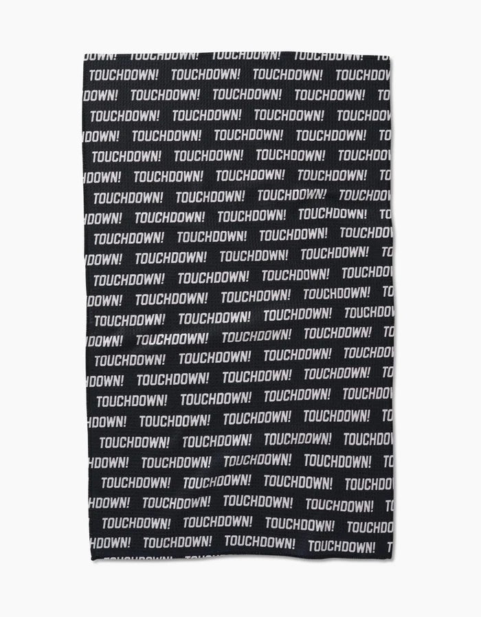 The GEOMETRY Touchdown tea towel is made from recycled materials and features TOUCHDOWN! in bold white uppercase letters, printed repeatedly across its black Geoweave fabric in a striking horizontal pattern.