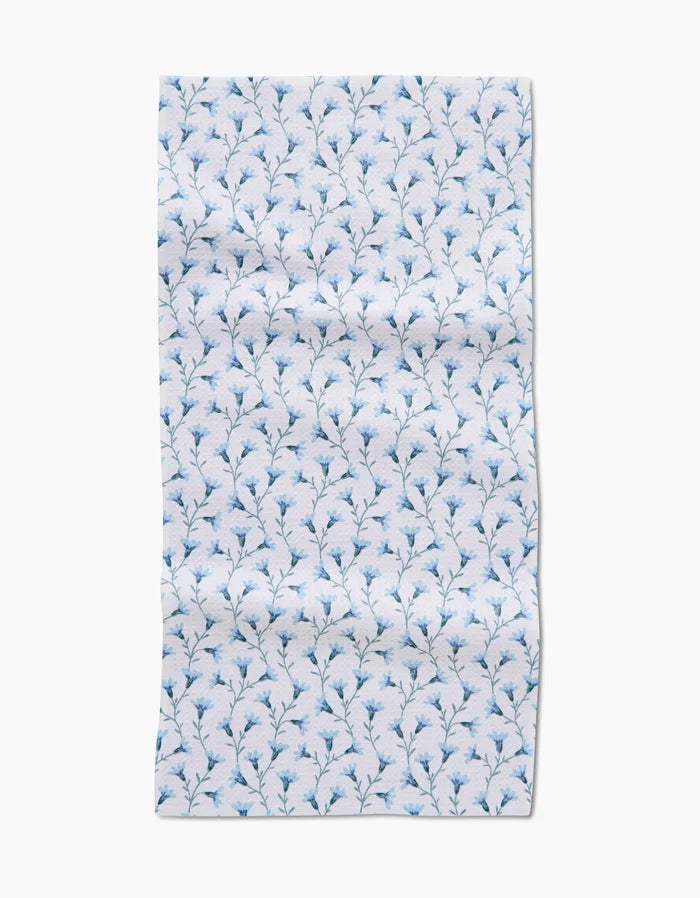 The Trailing Flowers in Blue Bar Towel by Teri the Butter features small blue floral branches evenly spaced on white Geoweave fabric, with visible edges and a slightly wrinkled appearance.
