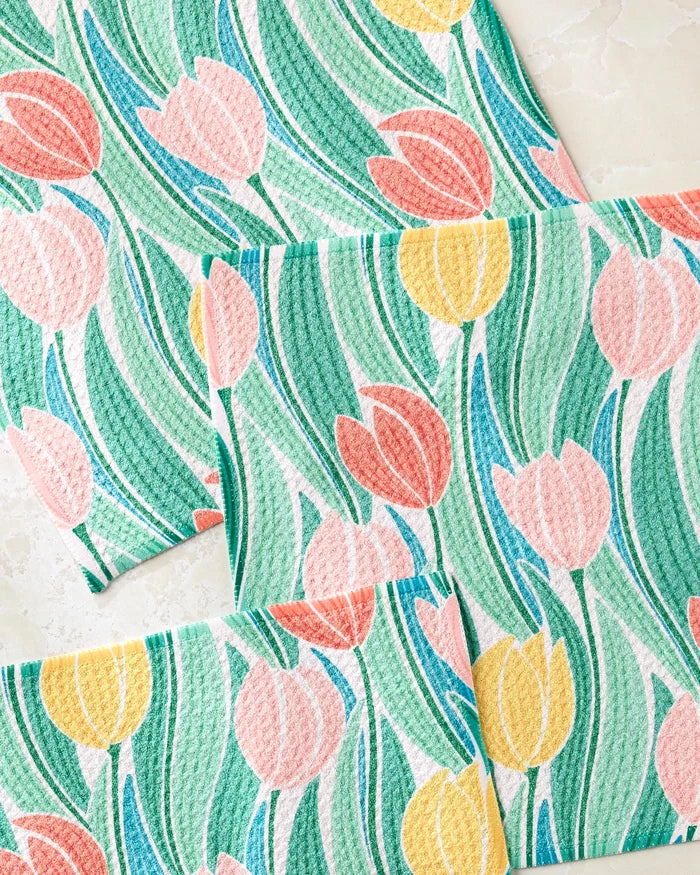 The Tranquil Tulips dishcloth set by Sarah Daugherty includes four rectangular, super-absorbent towels featuring colorful pink, yellow, and green tulip flowers with long curving leaves on a light background.