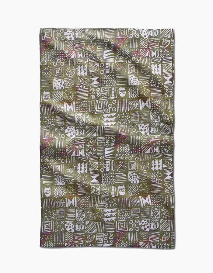 The Taryn Brennan Tribal Symbols tea towel is a rectangular Geoweave fabric with a green background, displaying white hand-drawn geometric and abstract patterns in squares, and is crafted from recycled materials.