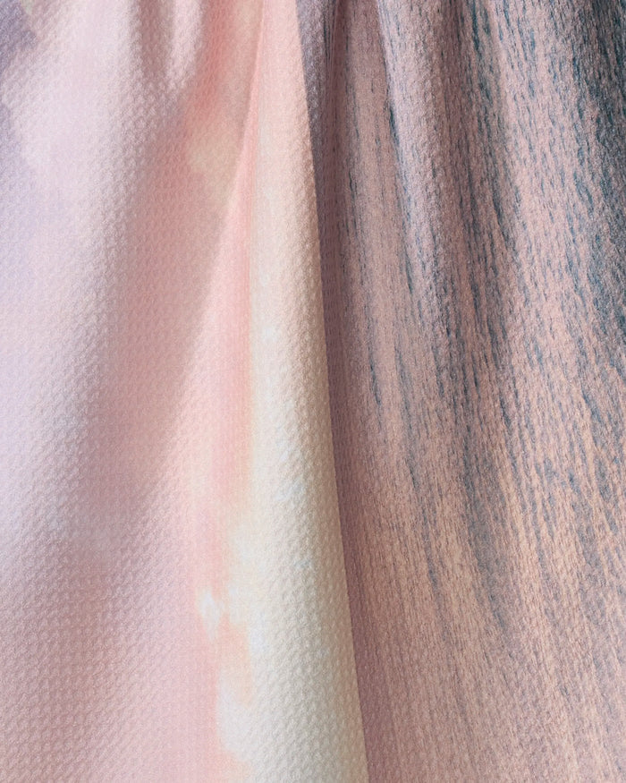 Close-up of Kait Hanson's Tropical Sunrise tea towel, featuring an absorbent, subtly textured weave and a soft pastel gradient blending pink, peach, and light gray tones.