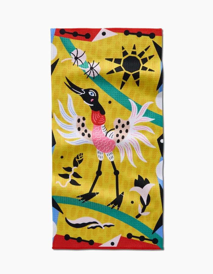 The Tuiuiú bar towel by Camila Leão is a vibrant rectangular Geoweave fabric towel featuring a stylized crane with spread wings, yellow background, abstract shapes, green curves, black sun, and floral and geometric designs. Ultra-absorbent and stylish.